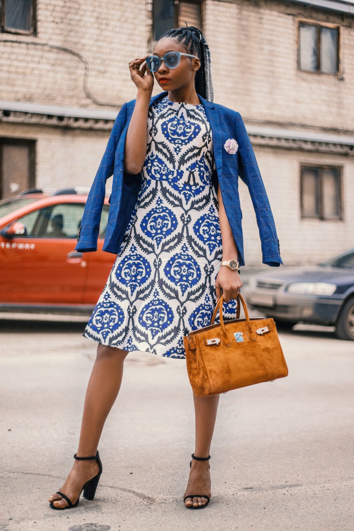Woman wearing white and blue floral dress carrying brown handbag