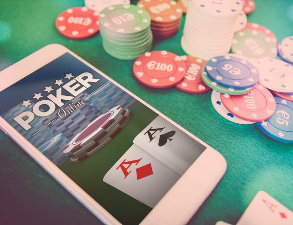 smartphone with poker website on screen, chips and cards over green poker table