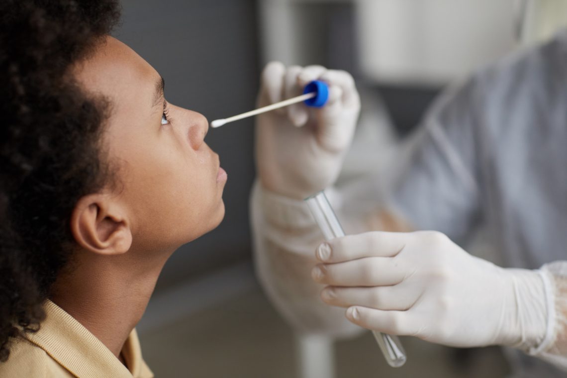 Side view closeup of African-American boy taking covid test during examination in medical clinic, copy space